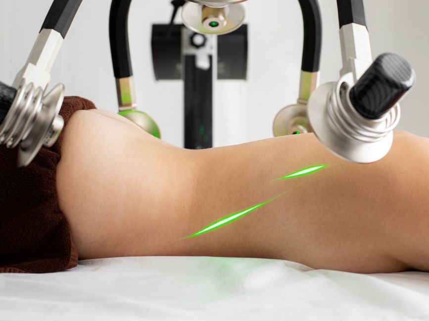 Paciente recebendo tratamento de fisioterapia com tecnologia a laser e equipamento de alta precisão na reabilitação muscular.