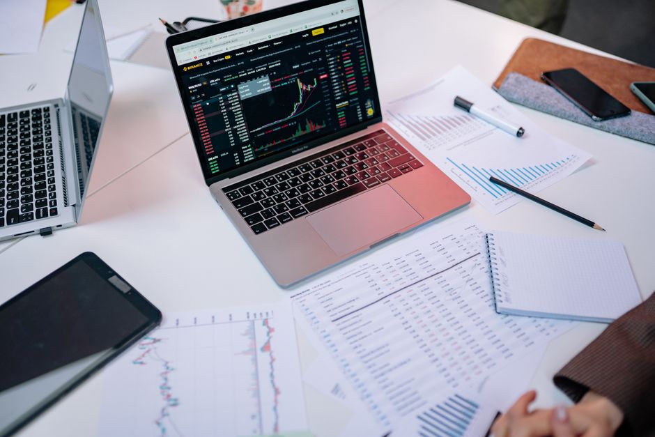 Imagem de uma estação de trabalho com laptops e relatórios financeiros, ideal para artigos sobre análise de investimentos e gestão financeira.