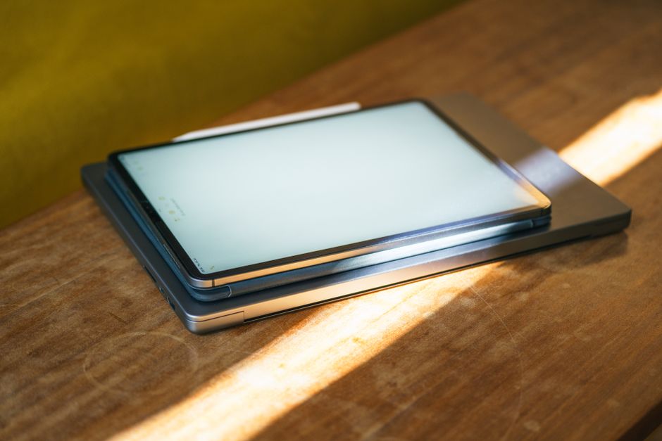 Imagem de dois smartphones empilhados sobre uma mesa de madeira em um ambiente bem iluminado, enfatizando tecnologia e comunicação digital.