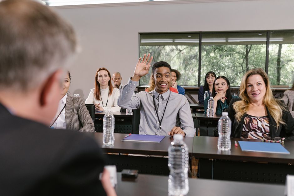 Pessoa participando de uma sessão de perguntas e respostas em uma reunião de negócios em um ambiente corporativo moderno.