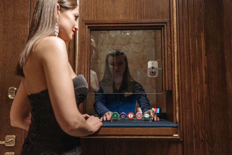 Mulher jogando pôquer em um cassino, refletida em um espelho de madeira ao while manipulando fichas de apostas.