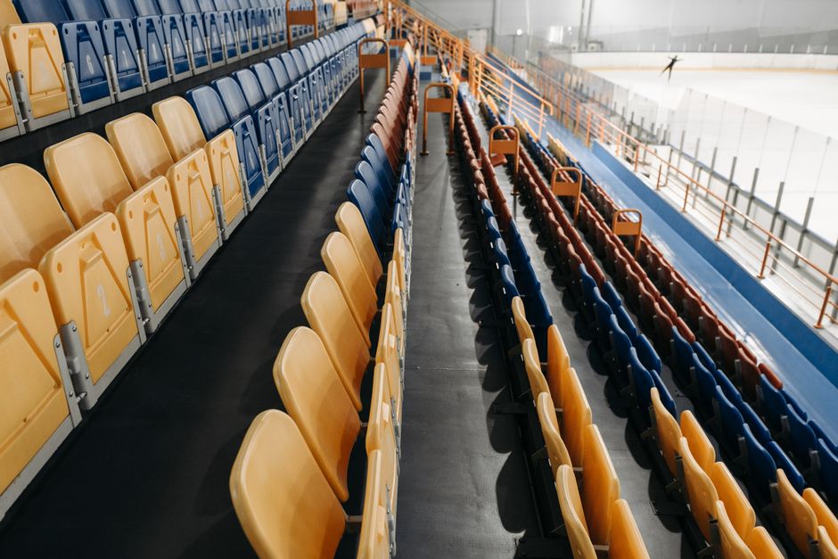Imagem de assentos vazios em uma arena ou ginásio esportivo, com destaque para a estrutura de arquibancada.