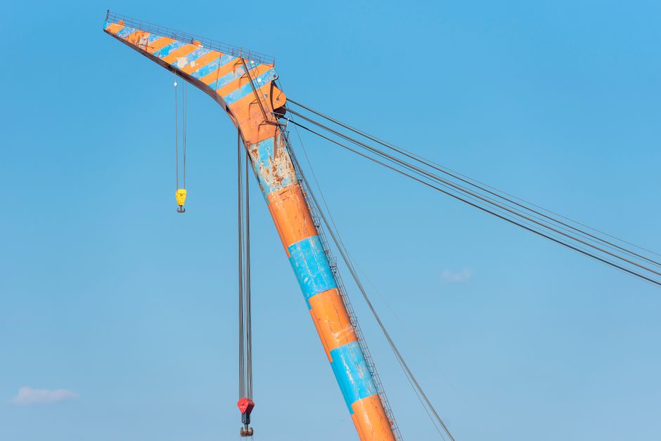 Imagem de uma grua de construção contra um céu azul, simbolizando engenharia e infraestrutura em obras civis.