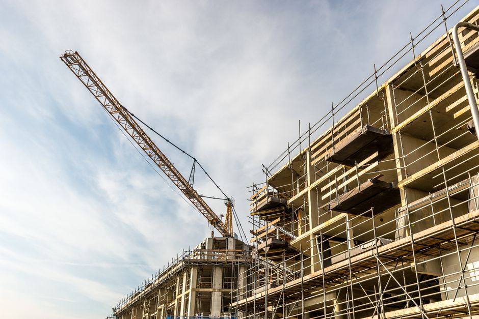 Imagem de um canteiro de obras com uma torre de guindaste em construção, representando temas de construção civil e infraestrutura.