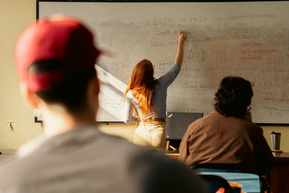Professora explicando conceitos de biologia para estudantes em uma sala de aula.
