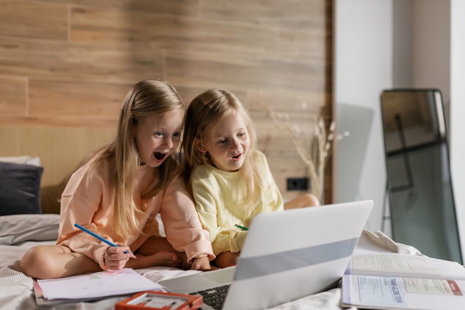 Duas crianças assistindo e se divertindo com algo em um laptop em um ambiente acolhedor e moderno.