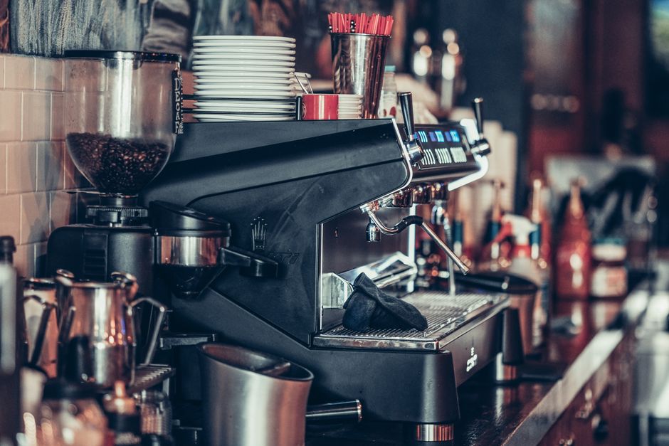 Imagem de uma máquina de café expresso em uma cafeteria, destacando o ambiente voltado ao consumo de bebidas specialty e experiência do cliente.
