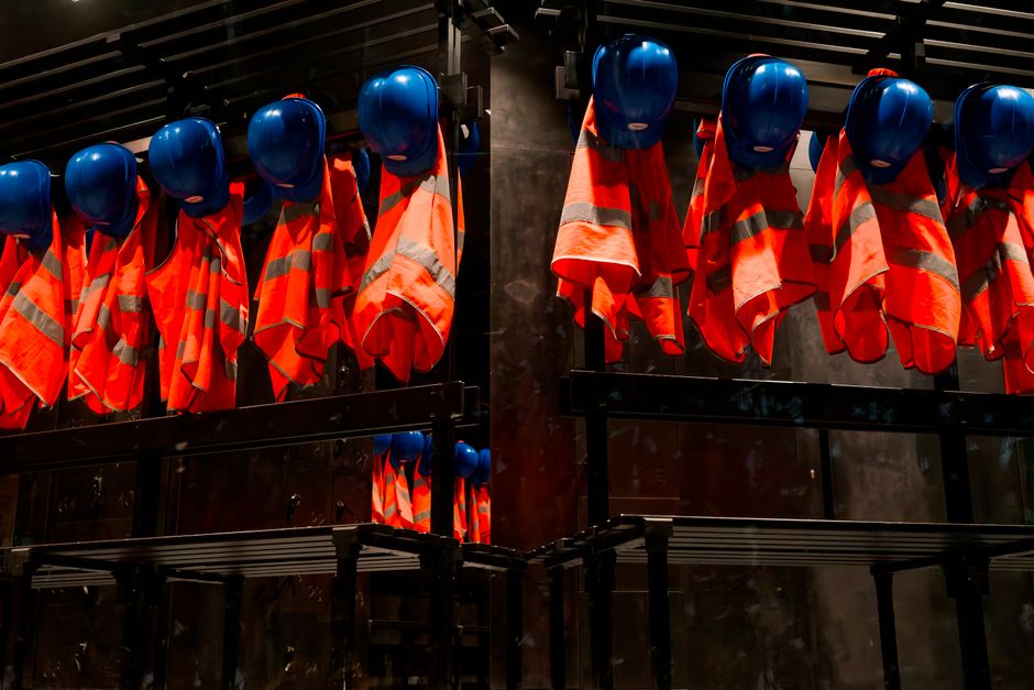 Capacetes e coletes de segurança pendurados, simbolizando segurança no trabalho e prevenção de acidentes