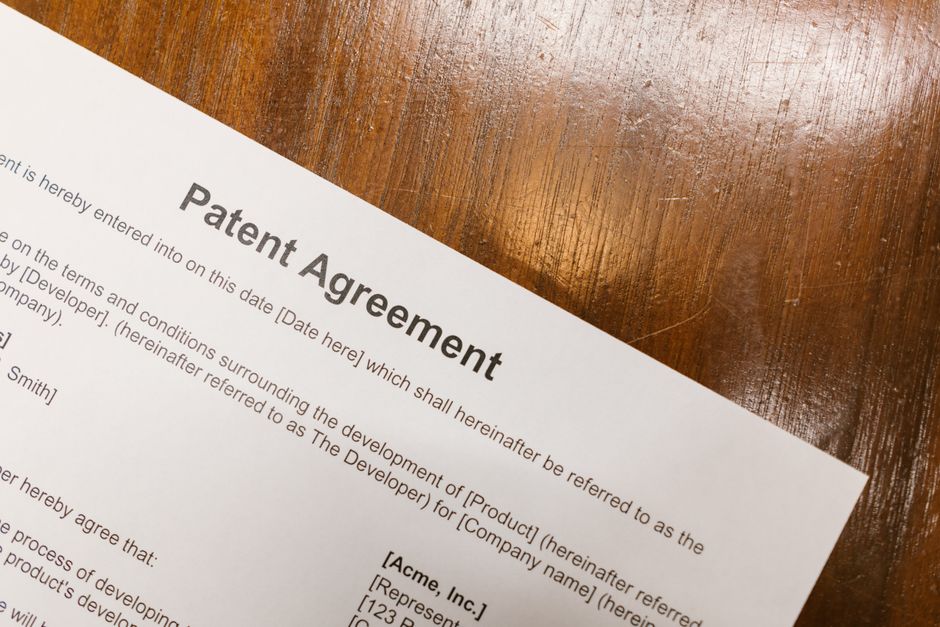 Documento de contrato de patente sobre uma mesa de madeira, simbolizando processos legais e registros de propriedade intelectual.