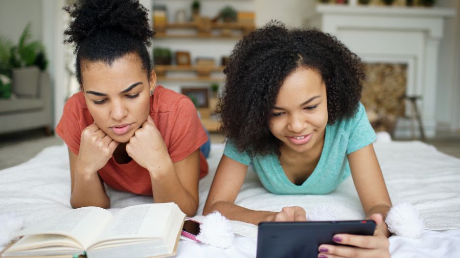 Duas jovens adultas estudando e utilizando tecnologia na rotina de estudos em casa.