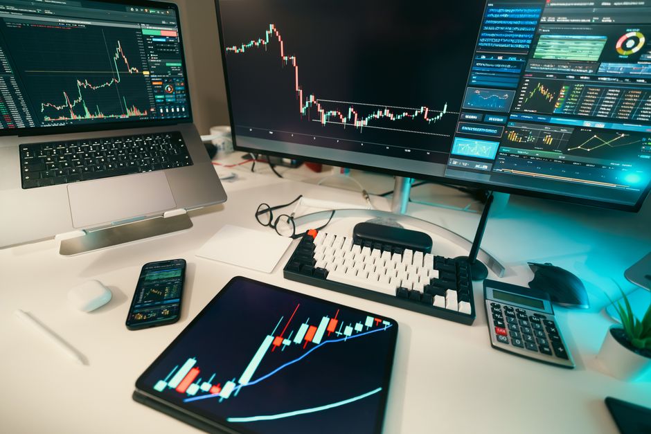 Setup de análise de dados financeiros com múltiplas telas exibindo gráficos e indicadores de mercado.