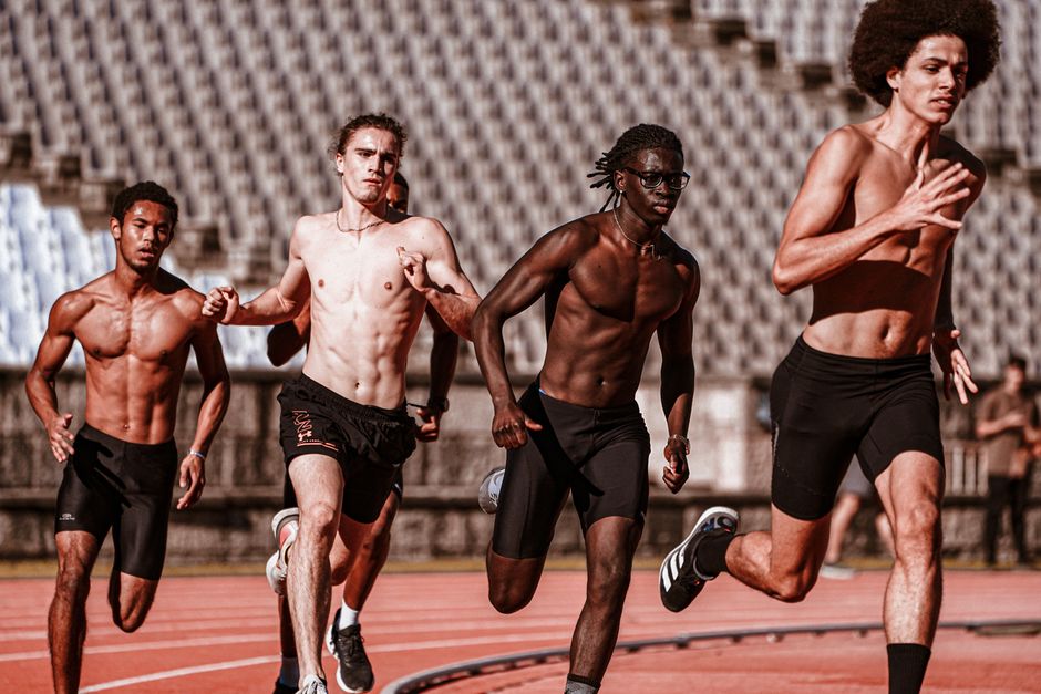 Grupo de atletas correndo em uma pista de atletismo, representando determinação e performance esportiva.