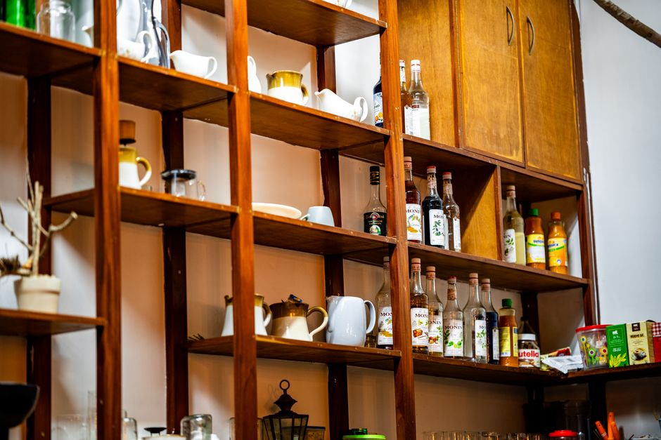 Estante de madeira repleta de utensílios de cafeteria, destacando a organização e variedade de bebidas e louças usadas no preparo de cafés especiais.
