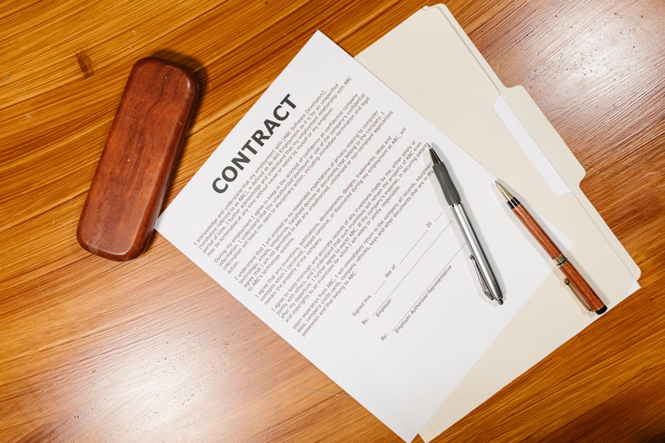 Imagem de contrato de trabalho com caneta e pasta, simbolizando assinatura e formalização de acordos comerciais.