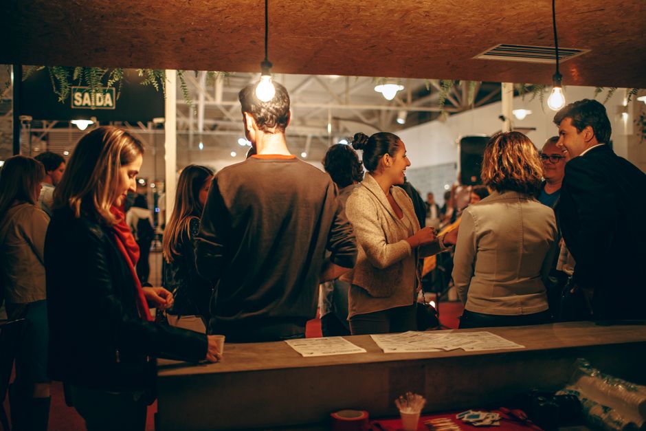 Grupo de pessoas conversando e socializando em um evento ou reunião social, transmitindo um ambiente de networking e interação social.