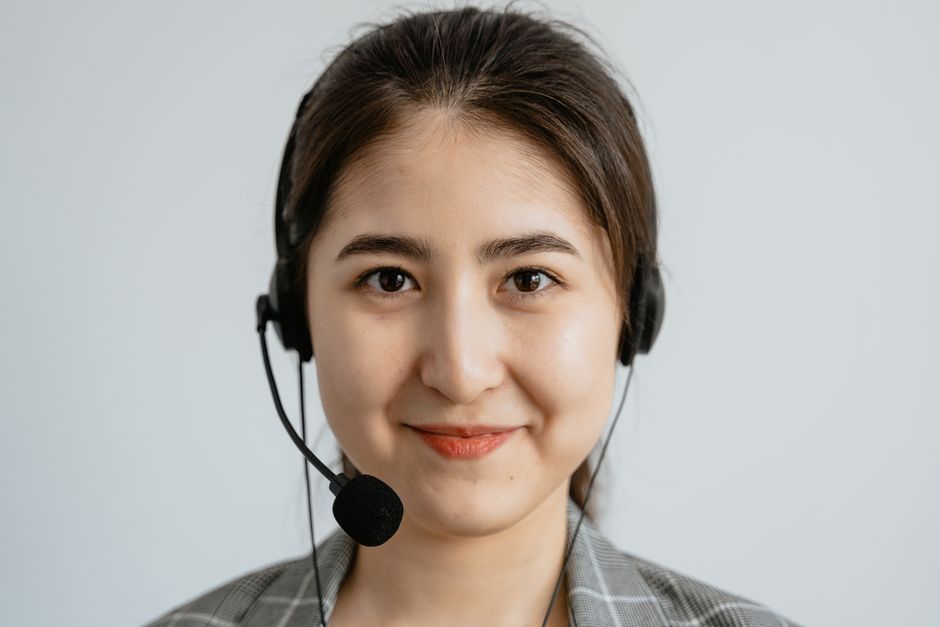 Mulher atendendo ao cliente com atendimento ao cliente ou suporte, usando headset e expressão cordial.