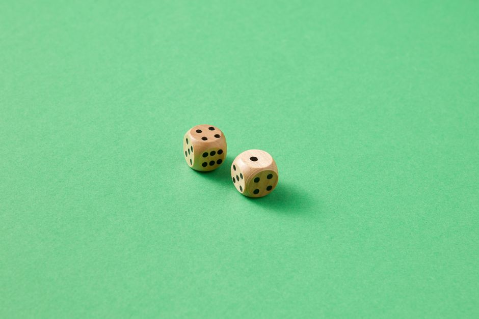 Imagem de dois dados em uma superfície verde, representando jogos de azar ou tomada de decisão aleatória.