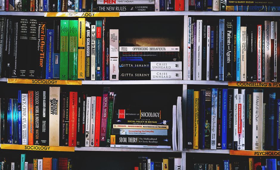 Estante de livros acadêmicos sobre sociologia, psicologia e aconselhamento, ideal para artigos de blog sobre estudos sociais e formação intelectual.