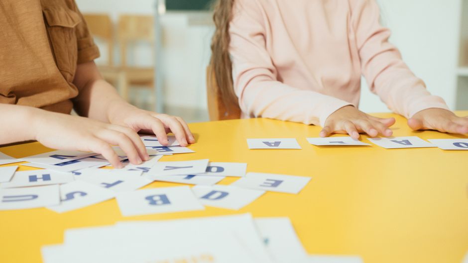 Crianças envolvidas em uma atividade de aprendizado com letras e palavras, promovendo o desenvolvimento cognitivo e escolar.