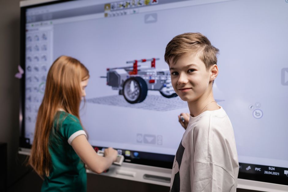 Crianças interagindo com uma maquete digital em sala de aula, focando no tema de educação, tecnologia e aprendizagem interativa.