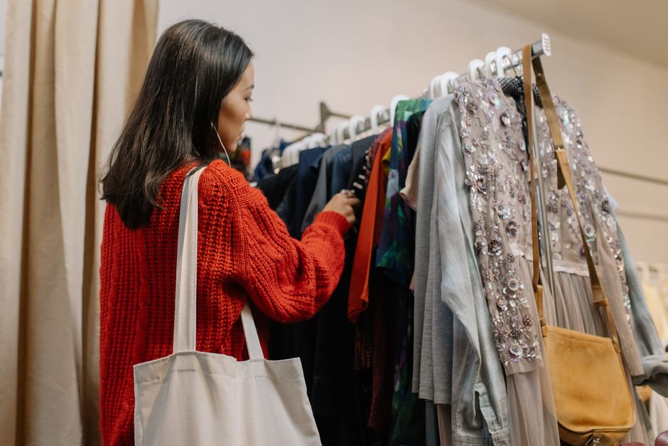 Mulher escolhendo roupas em uma loja de roupas, representando compras e moda feminina.