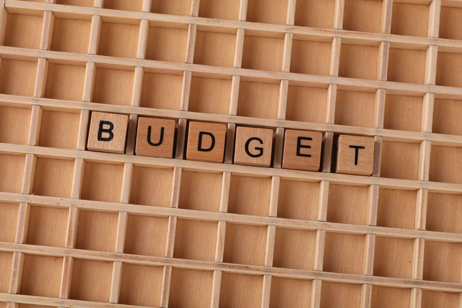 Imagem ilustrativa de planejamento financeiro e gestão orçamentária com blocos de palavras formando 'BUDGET' em uma grade de madeira.