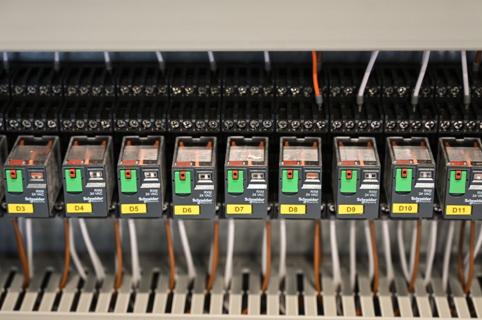 Imagem de um painel de controle elétrico com disjuntores e cabos, ilustrando sistemas de automação ou manutenção industrial.