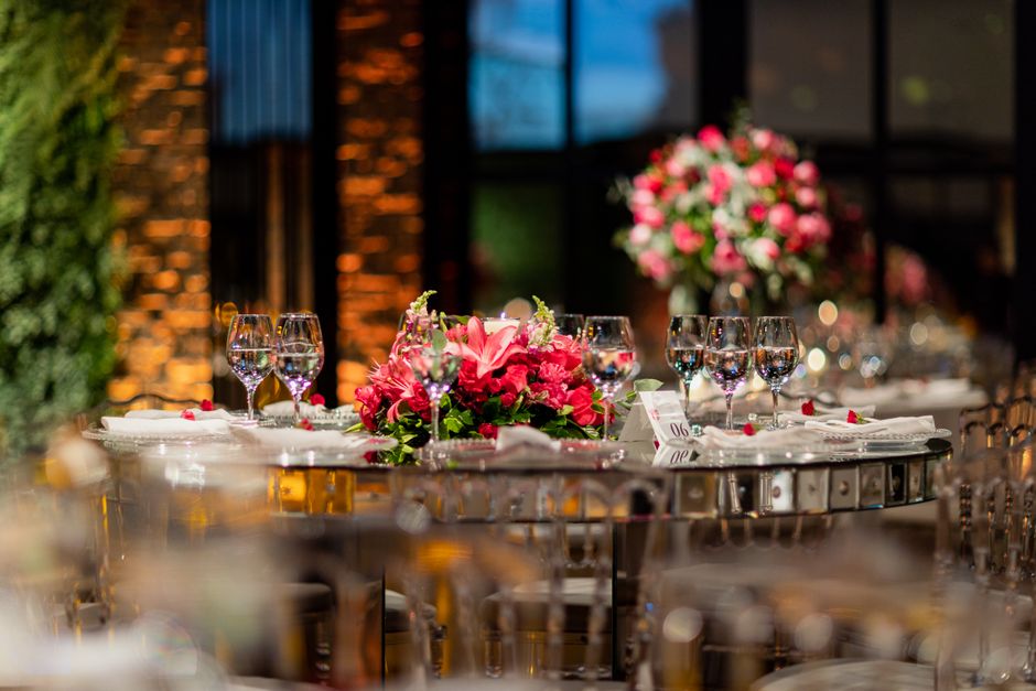 Mesa de casamento elegantemente decorada com flores e taças de vinho em um ambiente sofisticado à noite.
