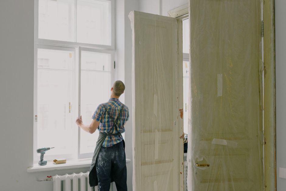 Profissional realizando manutenção ou instalação de janelas em espaço interno de uma residência em reforma ou construção.