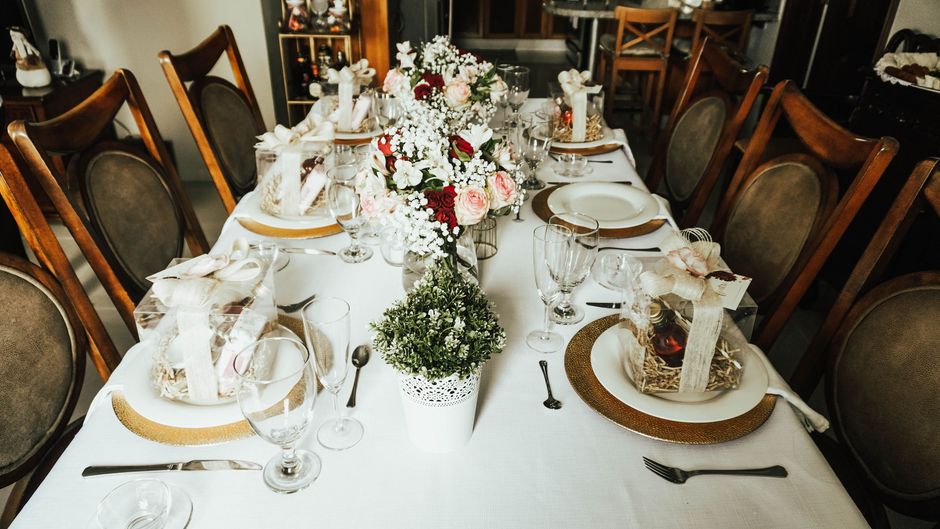 Mesa elegantemente arrumada para um evento social ou celebração, com decoração floral e detalhes sofisticados.