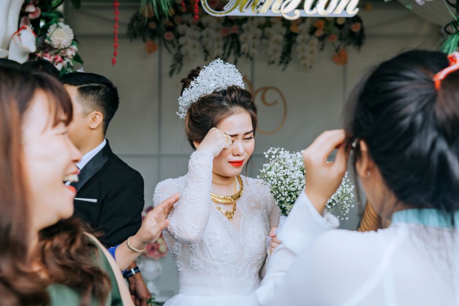 Mulher emocionada em momento de despedida ou agradecimento em uma cerimônia de casamento, cercada por pessoas felizes e entusiasmadas.
