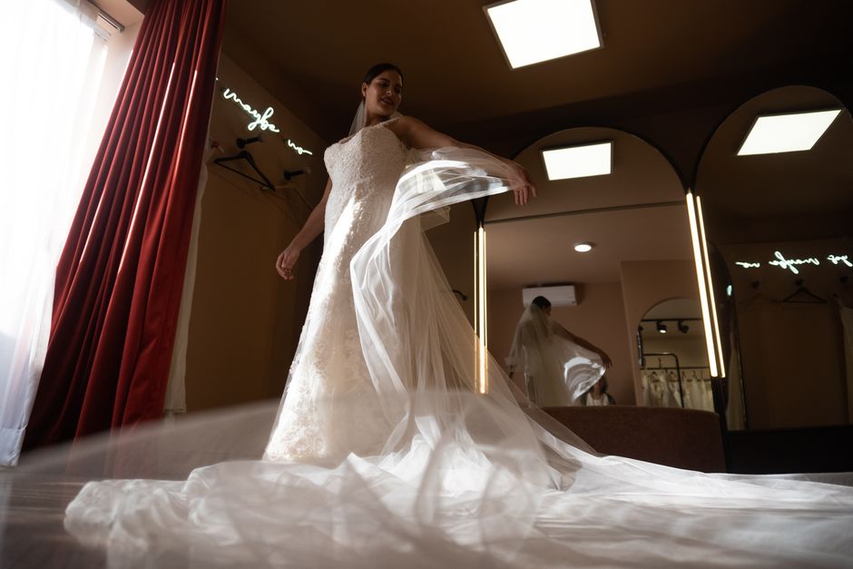 Noiva em um momento de preparação, exibindo seu vestido de casamento com um ambiente aconchegante e iluminação suave ao fundo.