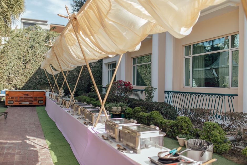 Mesa de buffet ao ar livre sob sombra, pronta para um evento ou festa ao ar livre, em ambiente residencial ou de lazer.