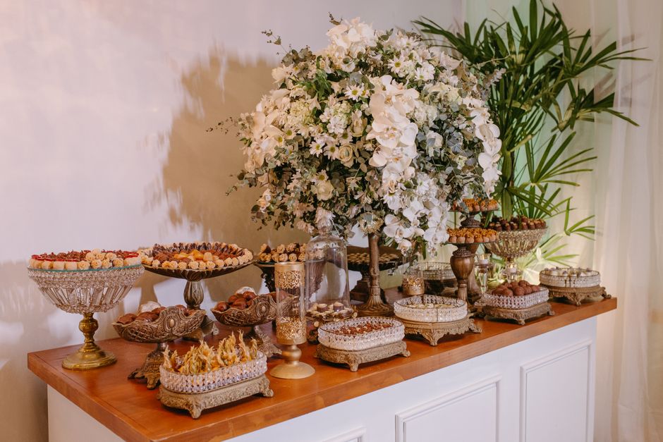 Mesa decorada com flores brancas e doces elegantes, ideal para festa ou celebração sofisticada.