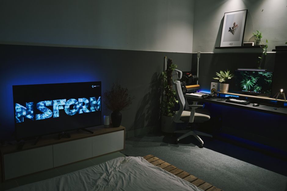 Um espaço de trabalho moderno e minimalista, com mesa de computador, plantas decorativas e iluminação ambiente para foco e criatividade.