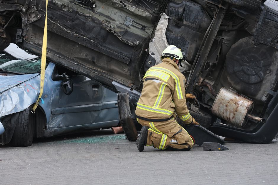 Bombeiro atendendo acidente de trânsito com carros envolvidos, destacando o trabalho de resgate e salvamento em situações de emergência.