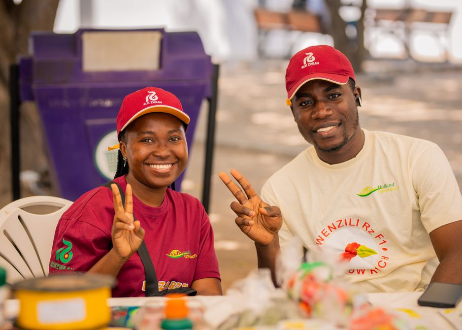 Jovens sorridentes participando de um evento ao ar livre, usando camisetas e bonés com logotipos, representando engajamento comunitário e voluntariado.