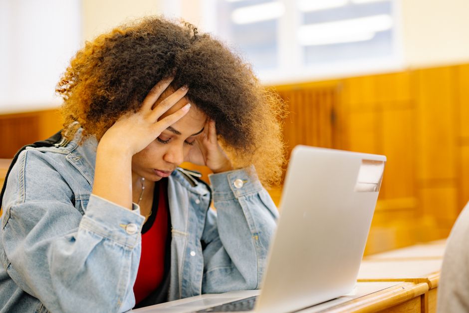 Mulher com expressão de estresse ou preocupação ao trabalhar em uma tarefa difícil no computador em um ambiente de estudo ou trabalho.