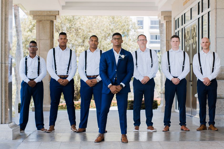 Grupo de homens vestidos formalmente para uma foto em ambiente externo, sugerindo profissionalismo e diversidade.