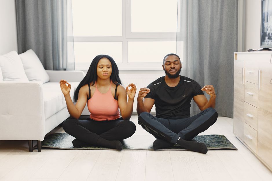 Homens e mulher praticando meditação em um ambiente doméstico para promover o bem-estar e a saúde mental.