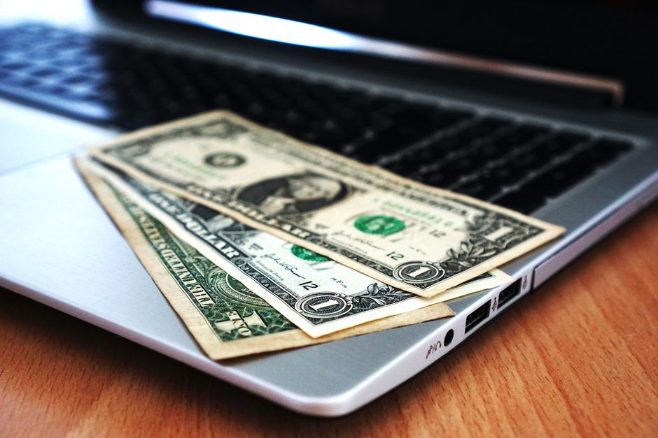 Imagem de dinheiro sobre o teclado de um laptop, simbolizando temas de finanças digitais, pagamento online ou economia colaborativa.