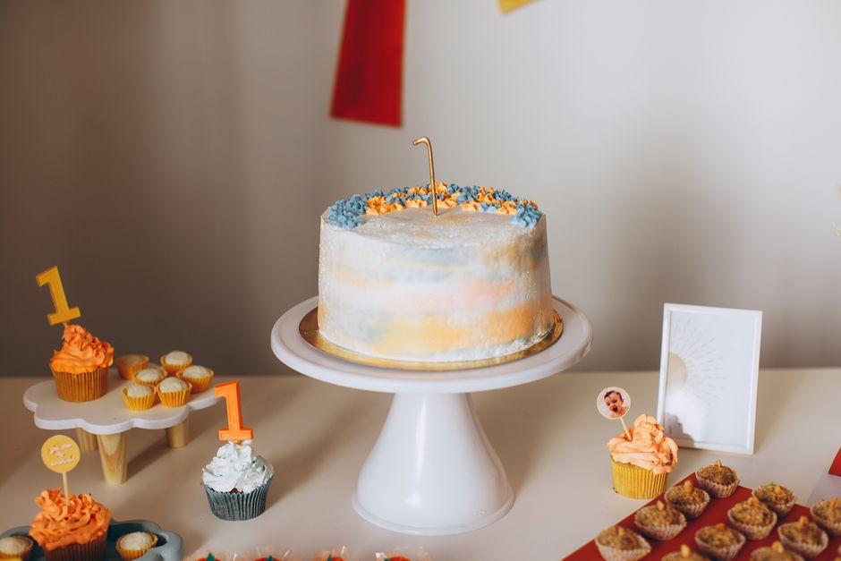 Imagem de uma mesa decorada com bolo de aniversário e cupcakes decorativos, ideal para comemoração infantil ou festiva.