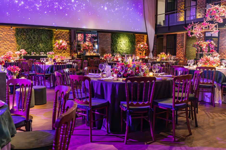 Espaço elegante decorado para evento social ou casamento, com iluminação suave, mesas decoradas com flores e ambiente sofisticado