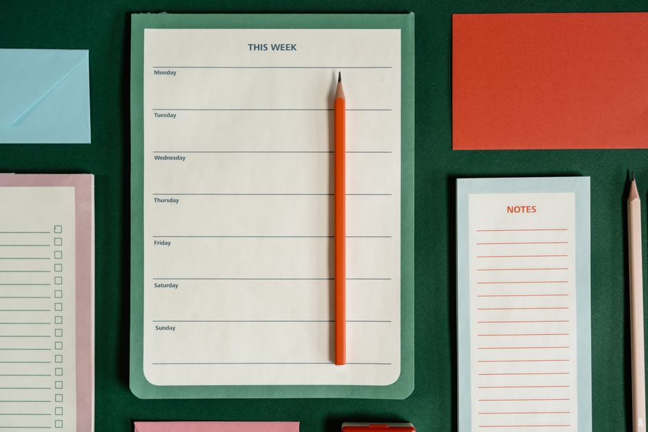 Imagem de uma organização semanal com planner, caneta e materiais de papelaria, ideal para artigos sobre gestão de tempo e produtividade.