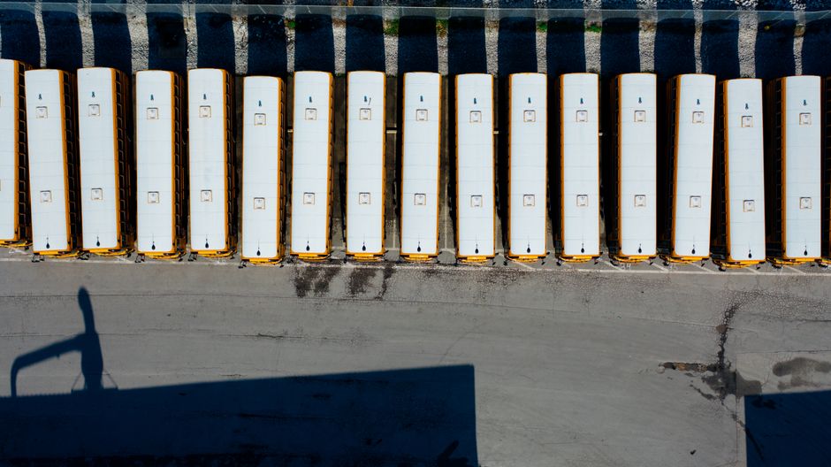Imagem aérea de linhas de ônibus estacionados em uma área urbana, destacando a organização do transporte público na cidade.