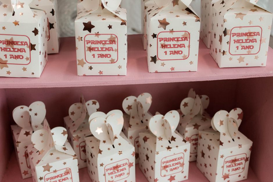 Caixas decorativas de festa para aniversário de uma princesa, com tema de estrelas e cachepôs em rosa, preparadas para a celebração de um ano de idade.