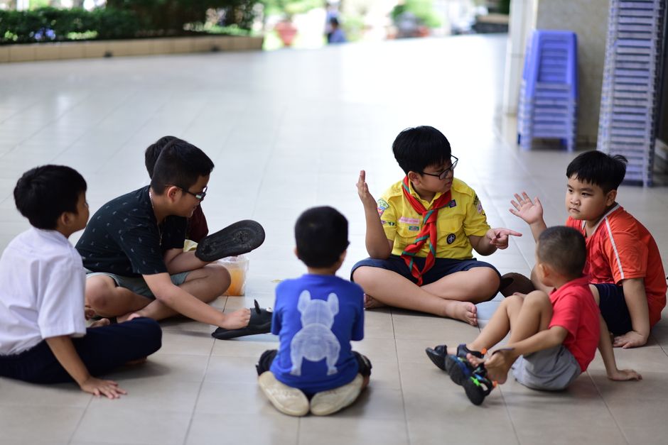 Grupo de crianças conversando e brincando ao ar livre, promovendo interação social e desenvolvimento infantil.