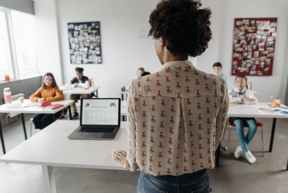 Professora conduzir uma aula em sala de aula com estudantes, focando no ensino e aprendizagem.
