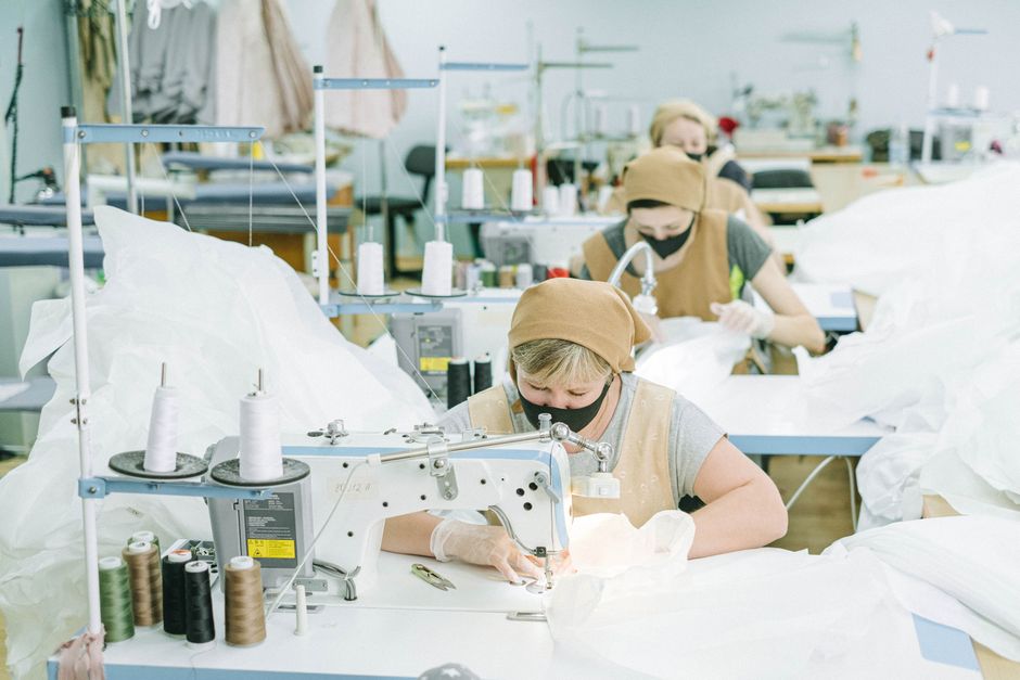 Equipe de costureiras trabalhando na confecção de roupas em uma indústria de moda sustentável.