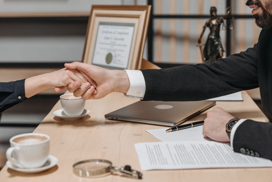 Imagem de uma reunião de negócios onde duas pessoas estão se cumprimentando após uma assinatura, simbolizando fechamento de acordo ou parceria profissional.
